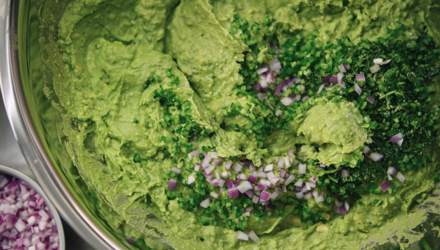 A video of fresh made Chipotle guacamole being stirred with all real ingredients including Hass avocados, salt, lime juice, cilantro, jalapeño, and red onion.